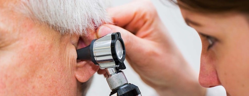 doctor examinging an elderly man's inner ear